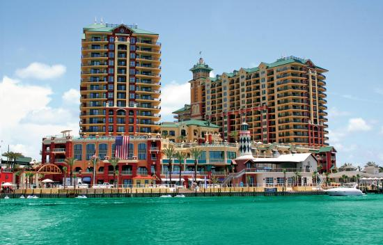 Private yacht cruising the Destin bay past HarborWalk Village where dolphins swim alongside boats