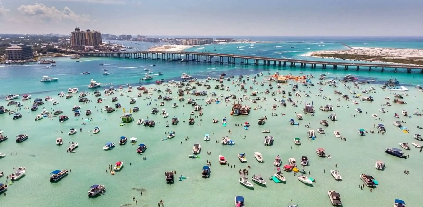 Family swimming in shallow clear water beside the yacht near Crab Island in Destin, Florida