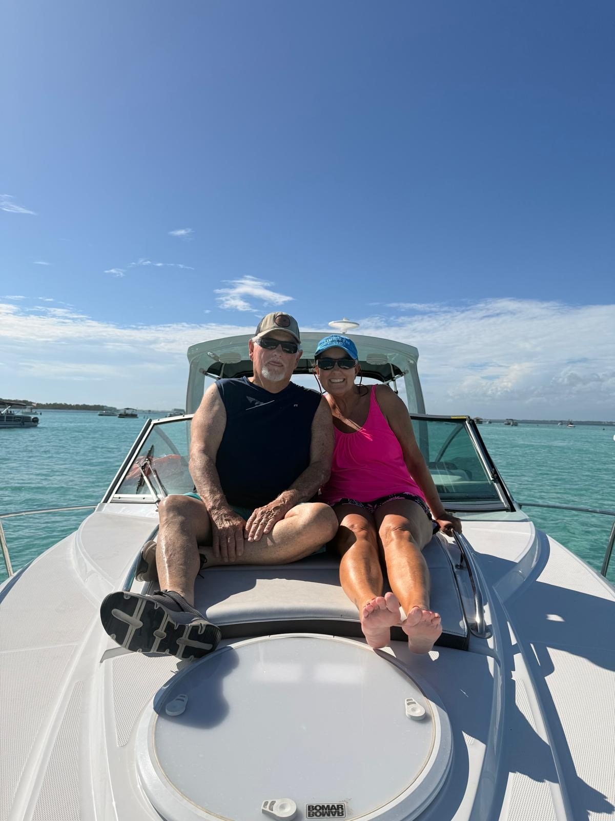 A couple enjoying the bow of the Salty Crook yacht at golden hour